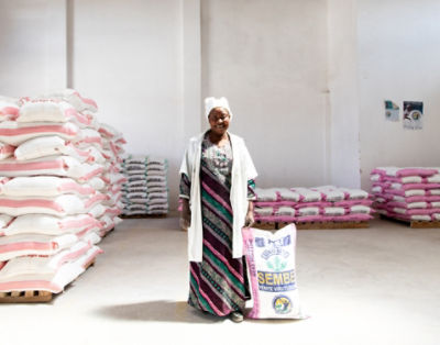 Woman standing next to a seed bag, among pallets of seed bags