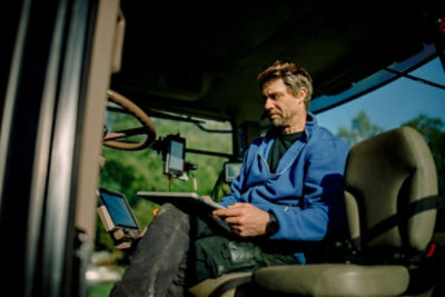 rman wearing blue jacket in tractor with notebook