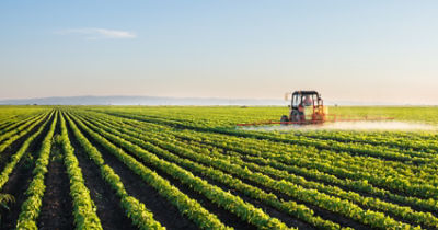 Tractor fumigando campo sembrado