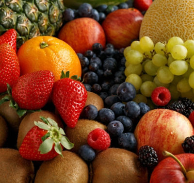 Variety of fresh fruits and berries on dark background: cantaloupe, melon, watermelon, blueberry, oranges, apple, strawberry, pineapple, mango, grapes and kiwi.