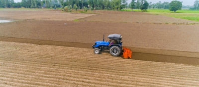 Tractor driving over dirt area