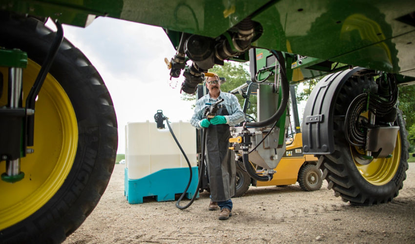 Farmer filling sprayer from Enlist tote