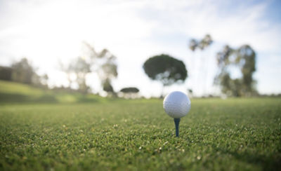 Tee box with a golf ball on a tee with trees in the background