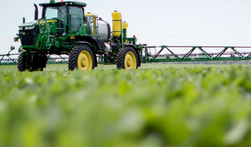 Green tractor sprayer in Enlist field