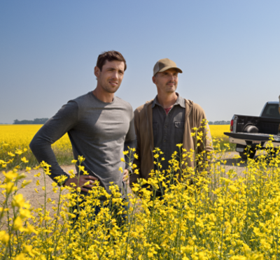men standing in canola field