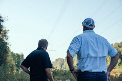 Two men facing away looking at a ulility right of way