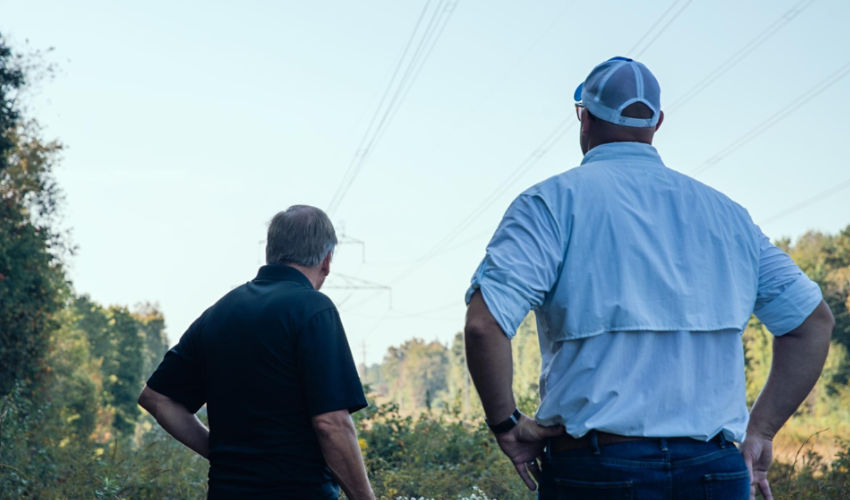 Two men facing away looking at a ulility right of way