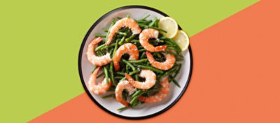A bowl full of green beans and shrimp on top, with two lemon slices.