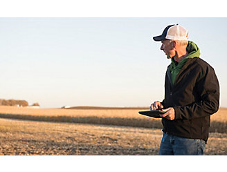 Man with tablet in harvested corn field