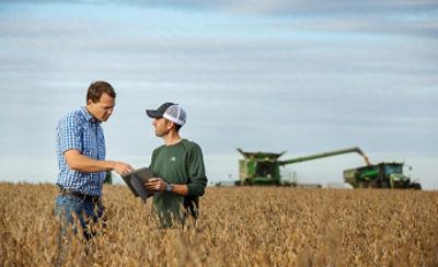 Representative and farmer talking in soybean field