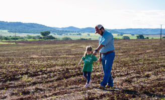 Pai e filha andando pelo campo.