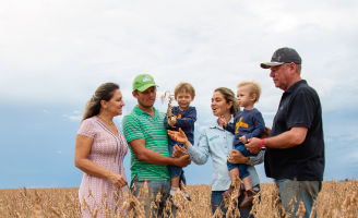 Família de 4 pessoas mais dois filhos no meio da lavoura de soja conversando.