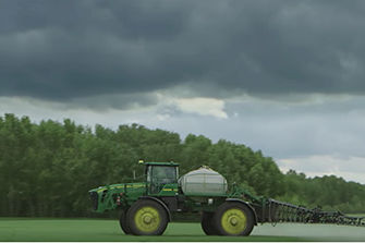 Sprayer in field spraying with dark clouds in background