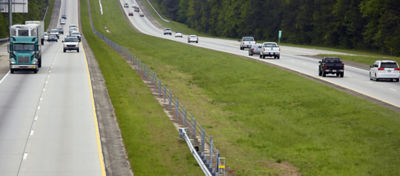 Image of two highways divided by grass, with cars and trucks driving