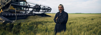 Bărbat în câmp lângă o mașină de treierat
